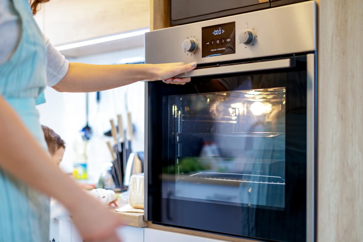 Una mujer prepara el horno para cocinar.