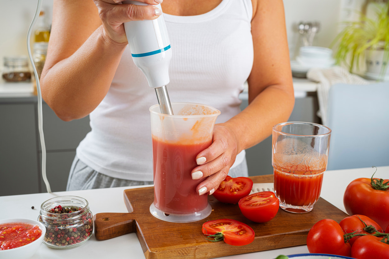Una mujer prepara batidos de fruta con la batidora.