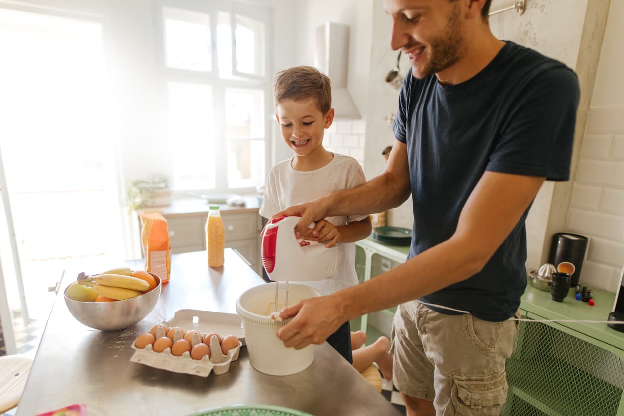 Un hombre prepara el desayuno en la batidora para su hijo.