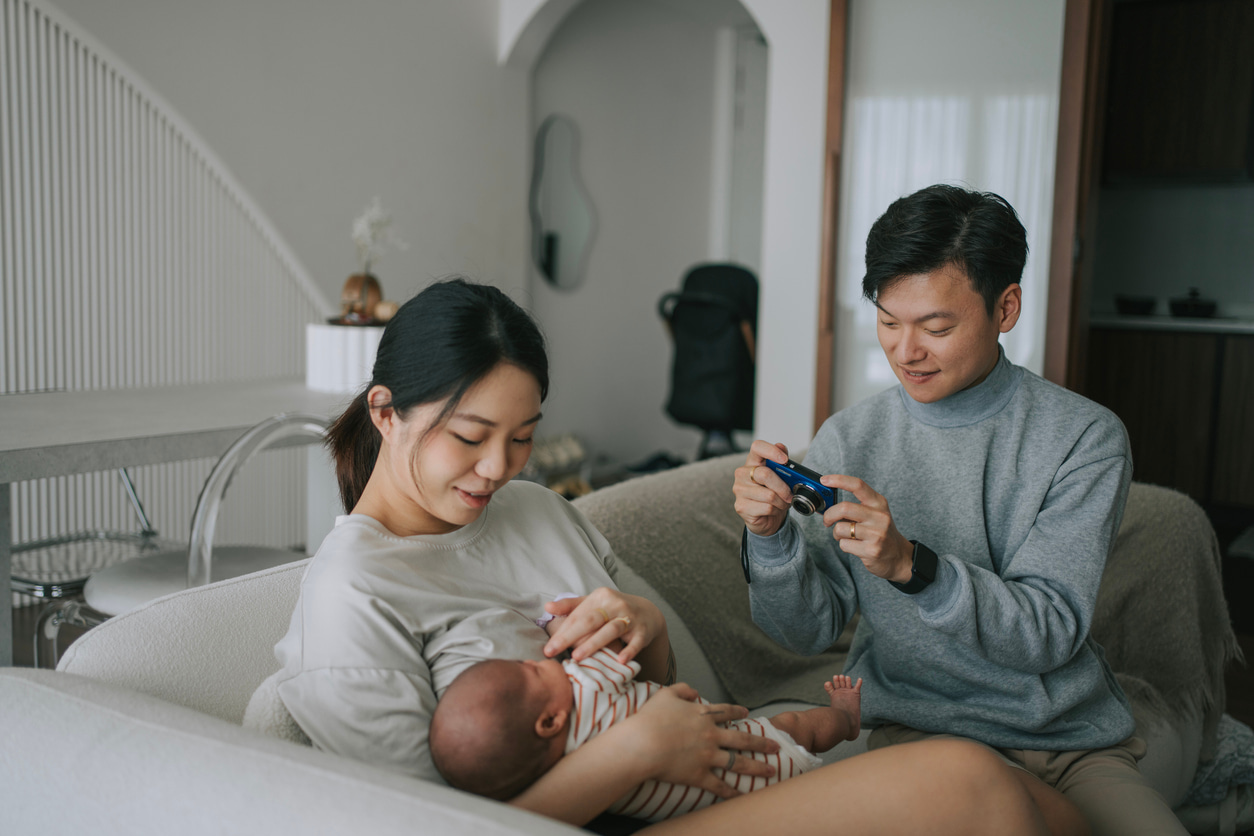 Un padre toma una foto de su hijo recién nacido en los brazos de su madre con una cámara compacta.