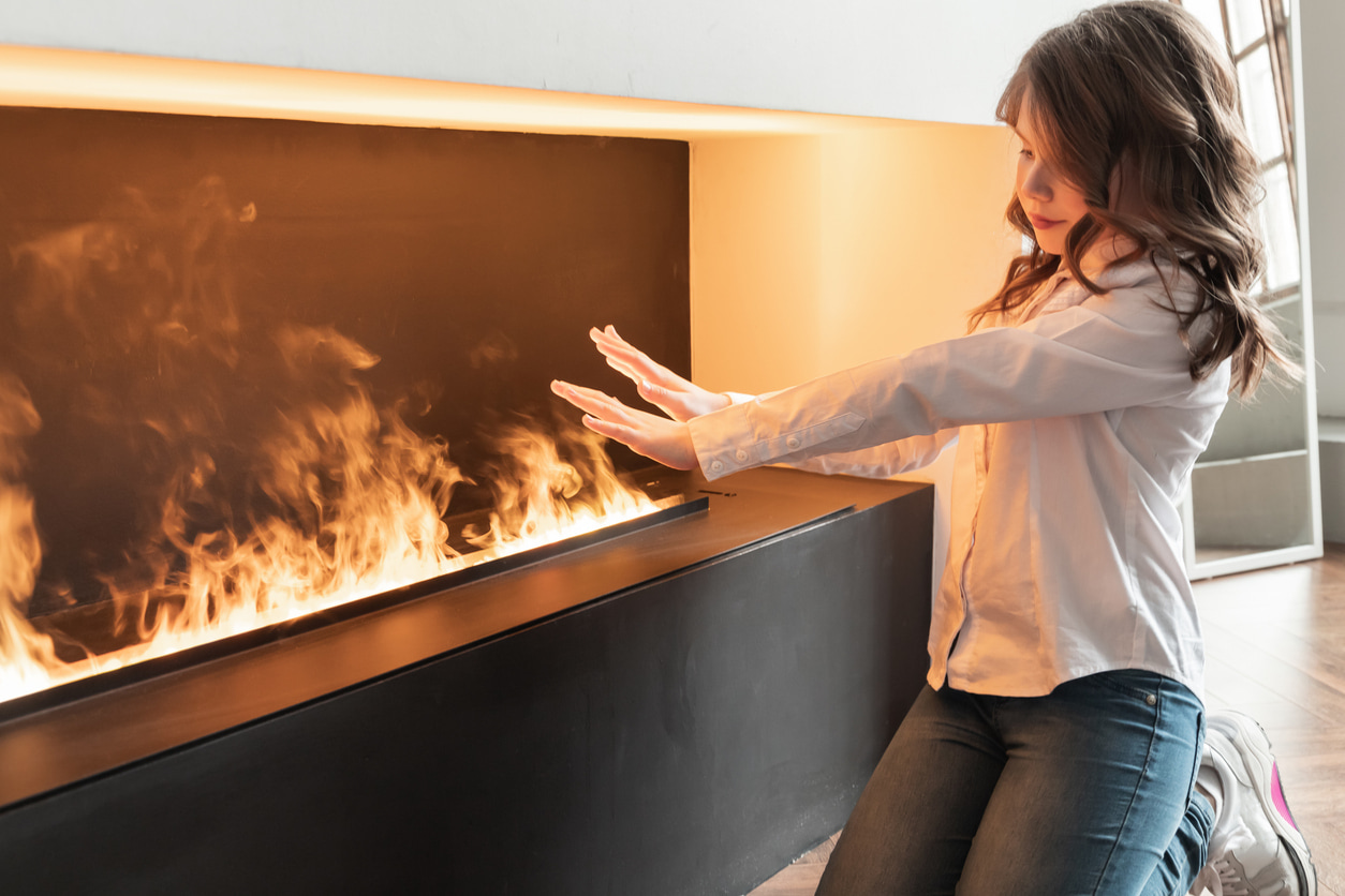 Una niña se calienta en su chimenea eléctrica.