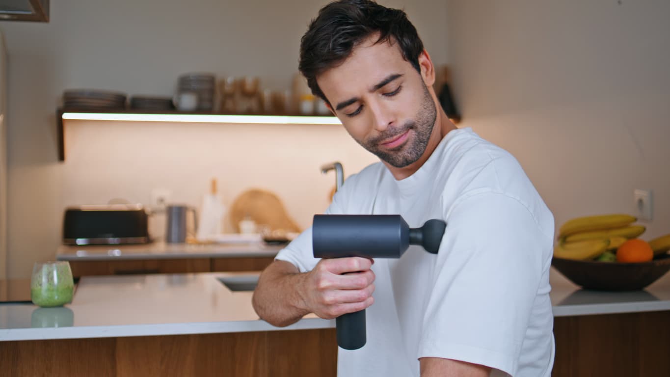 Un hombre utiliza un masajeador para relajar los músculos.