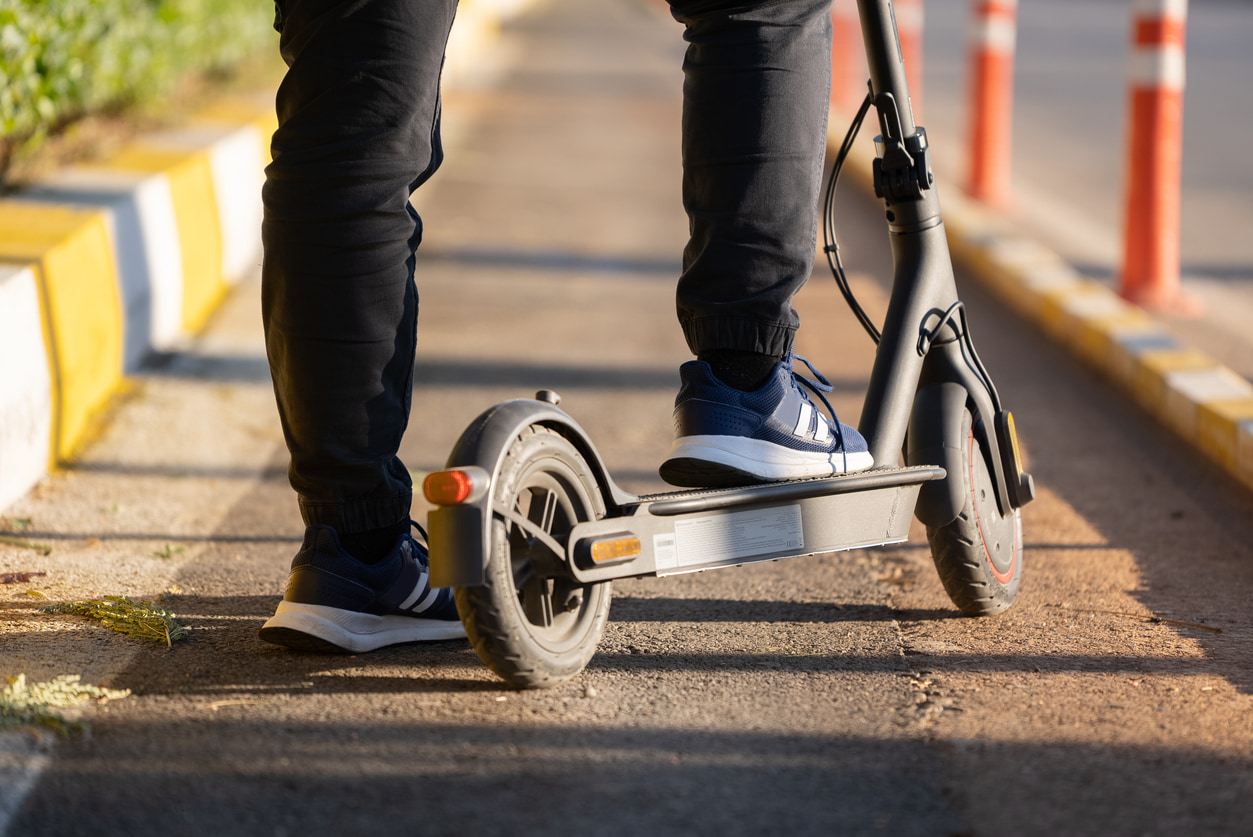 Un hombre se encuentra estático con el pie echado a tierra en su patinete eléctrico.
