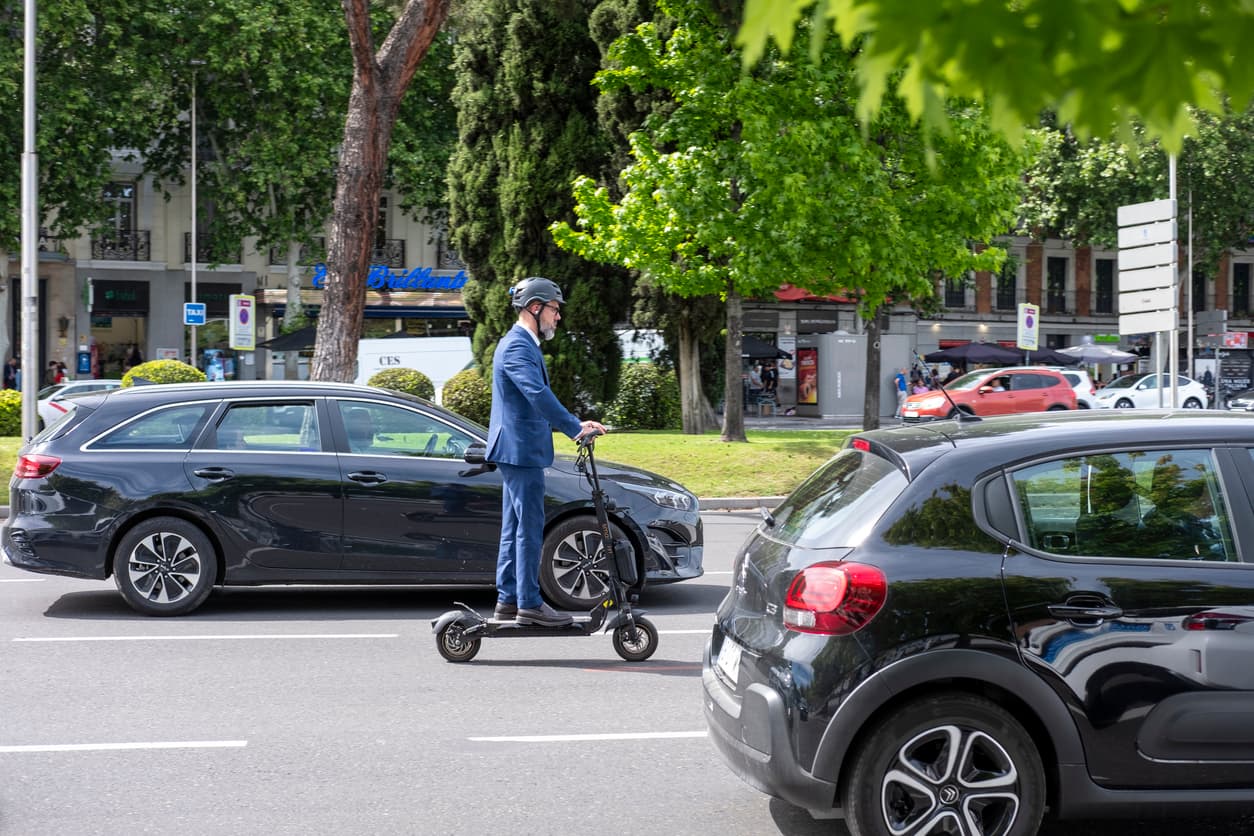 Un hombre trajeado circula en su patinete eléctrico por la ciudad.
