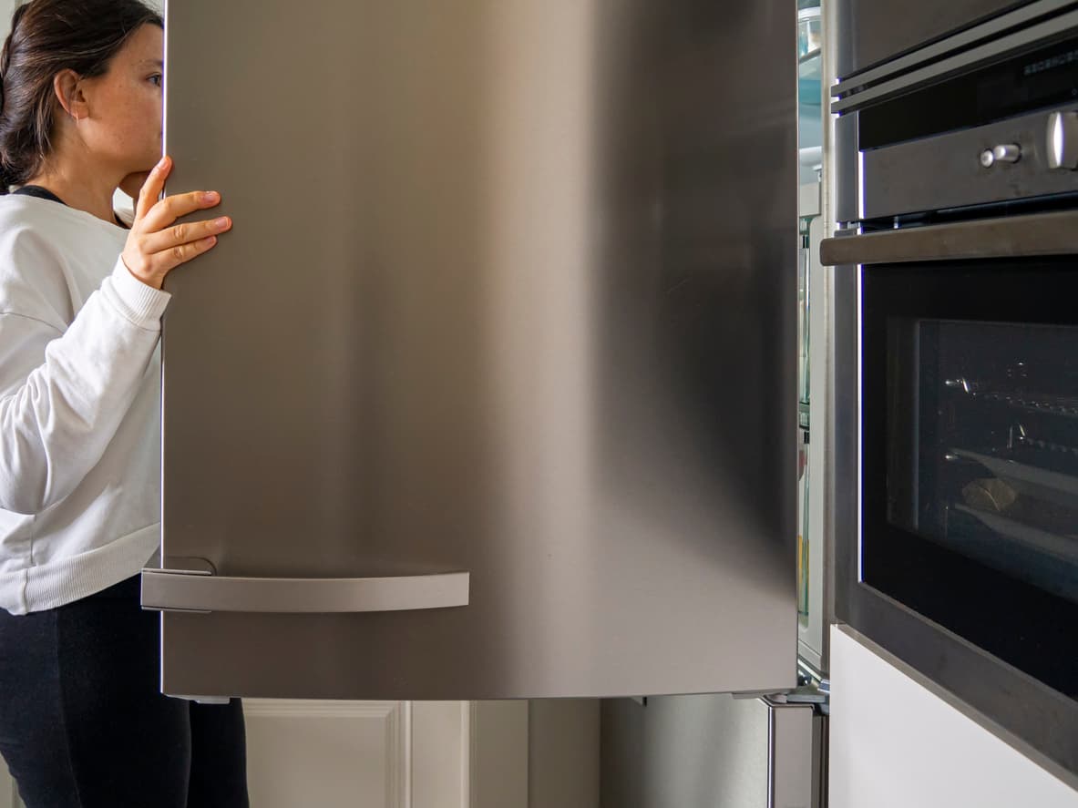 Una mujer abre la puerta del frigorífico para buscar comida.